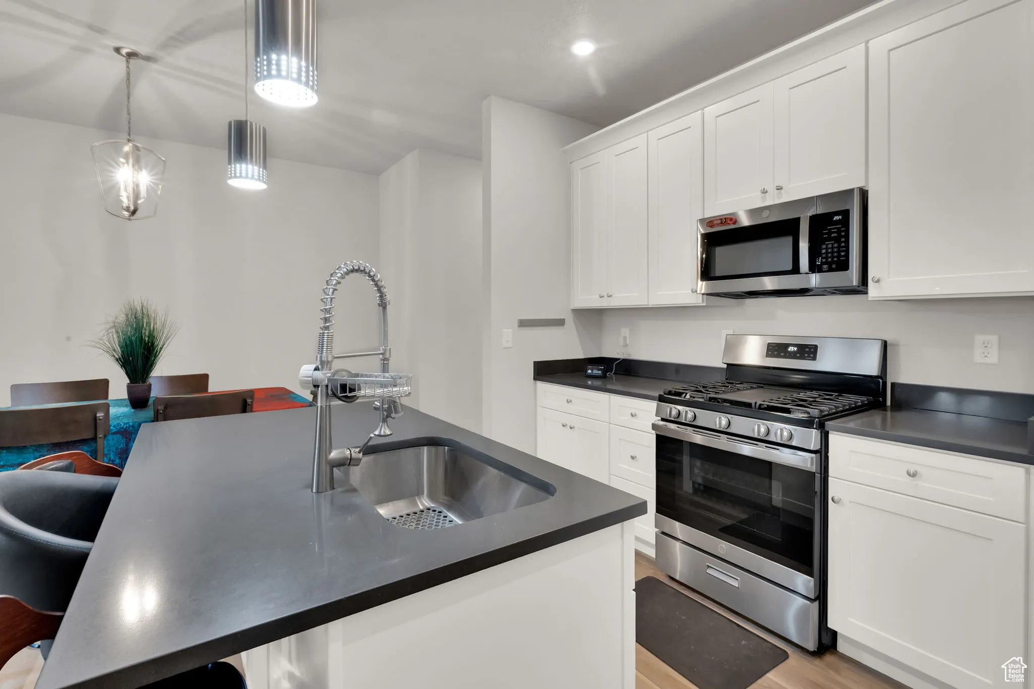 Kitchen with stainless steel appliances, a kitchen breakfast bar, white cabinetry, and light wood-style LVP floors