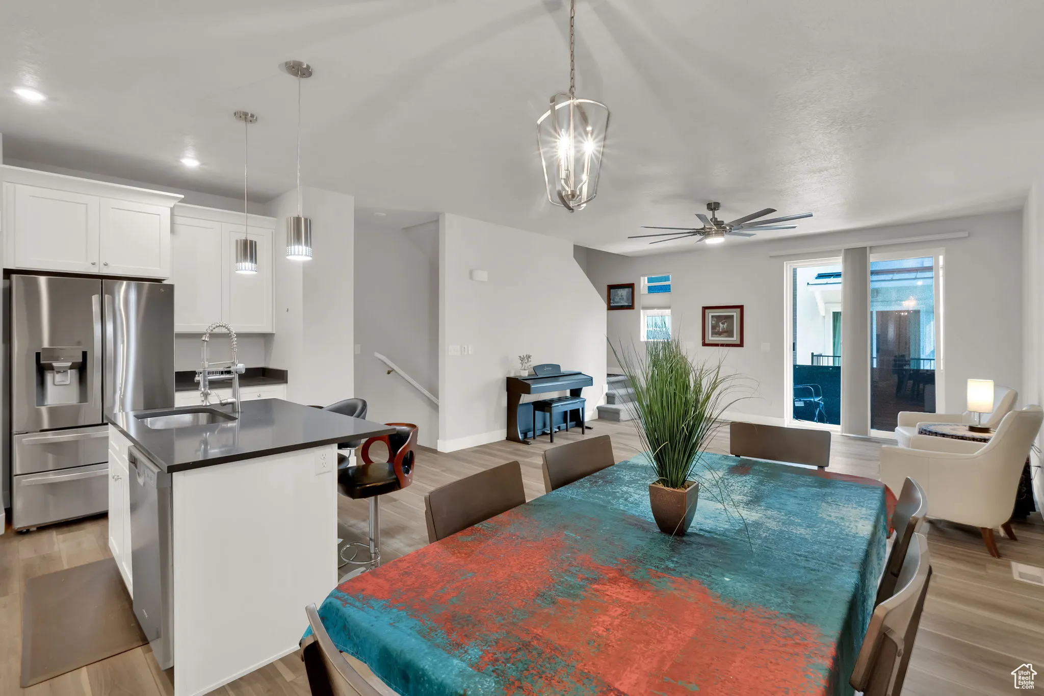 Dining space with light wood-style LVP floors, a large upgraded ceiling fan, stairway, and a chandelier