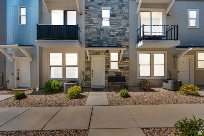 View of front of home featuring a balcony, stucco siding, and stone siding