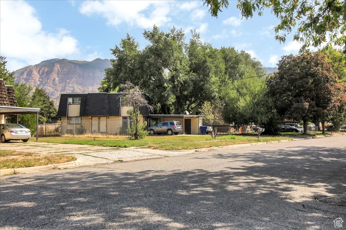 View of front facade featuring a mountain view, mansard roof, and driveway