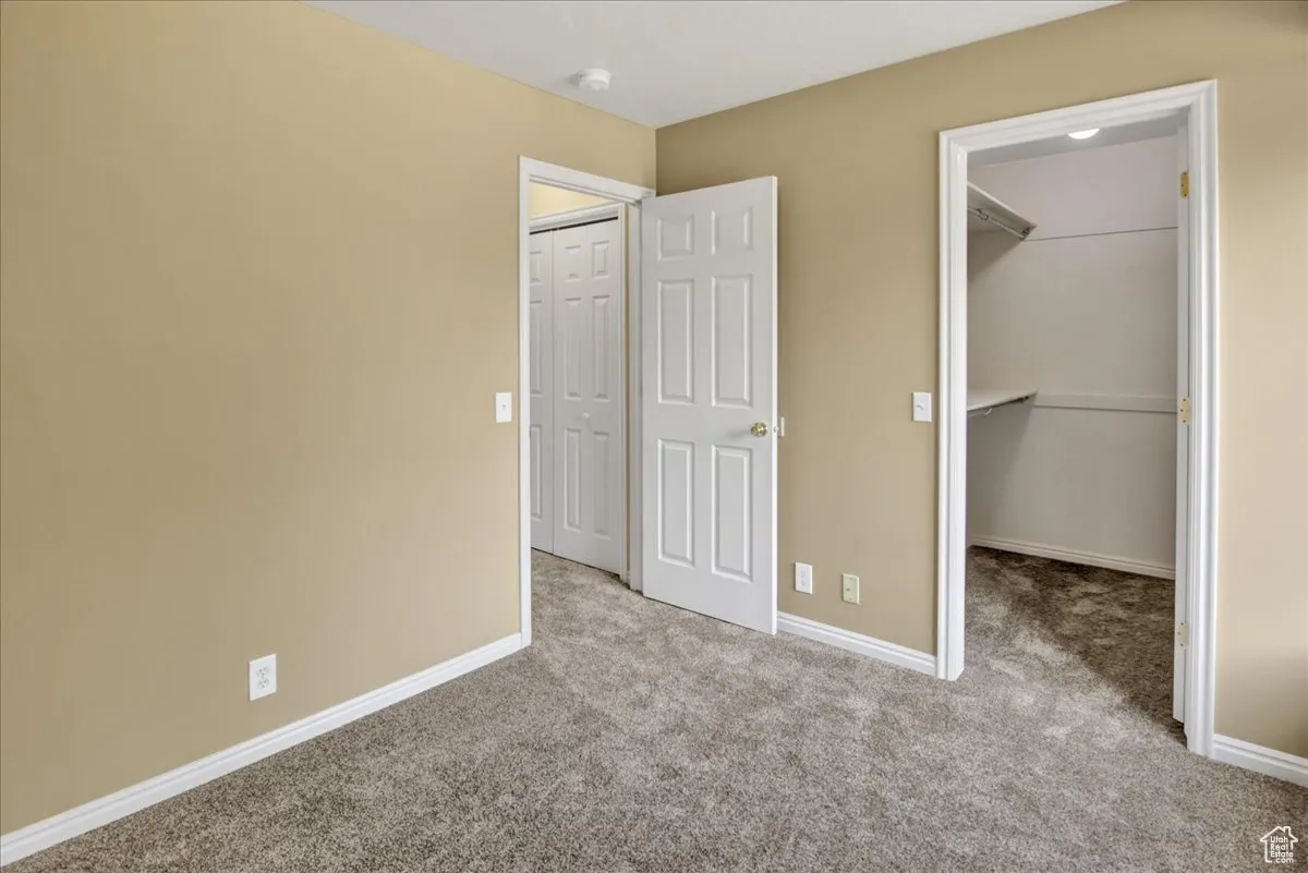 Unfurnished bedroom with carpet and a spacious closet