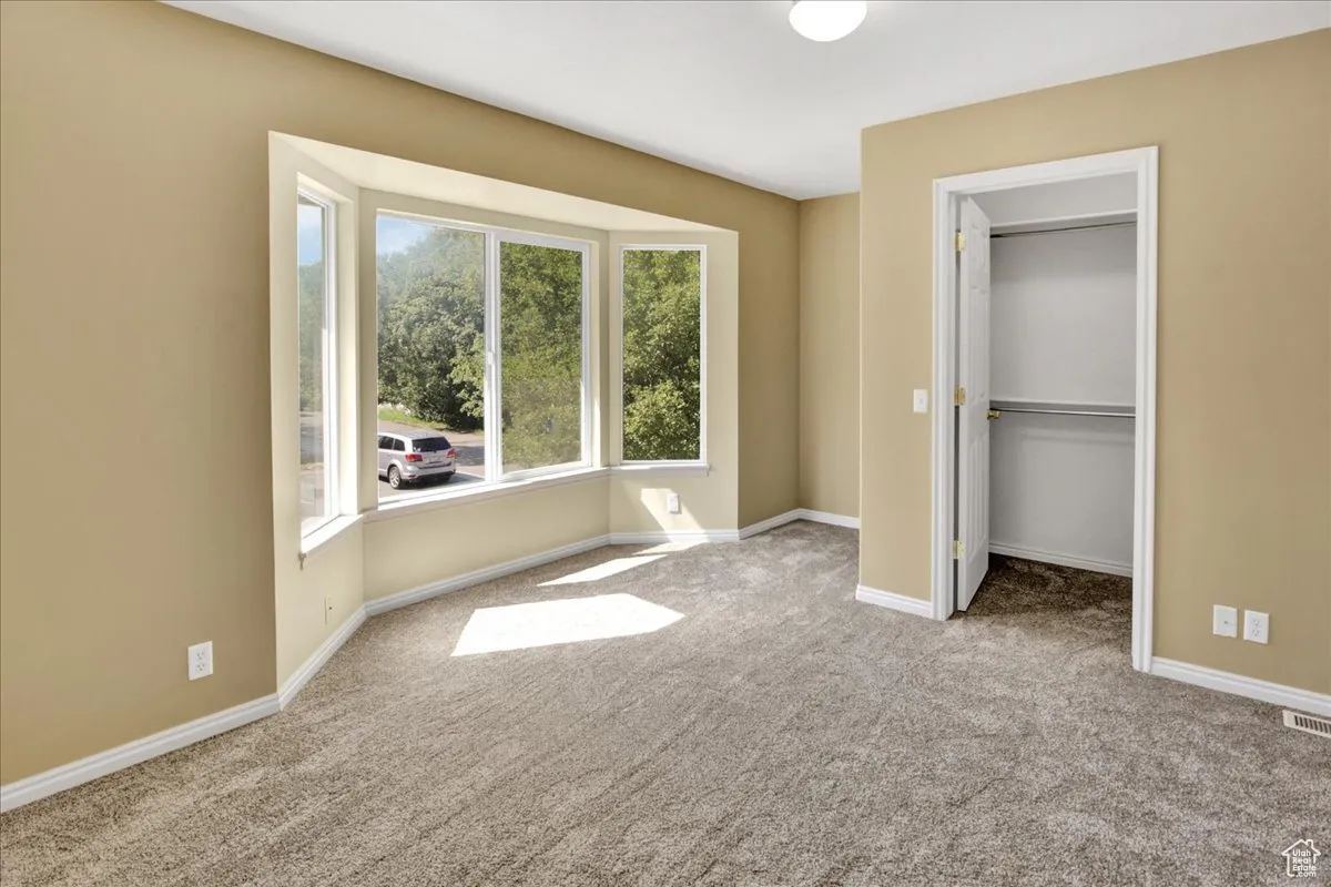 Unfurnished bedroom featuring a walk in closet and carpet floors