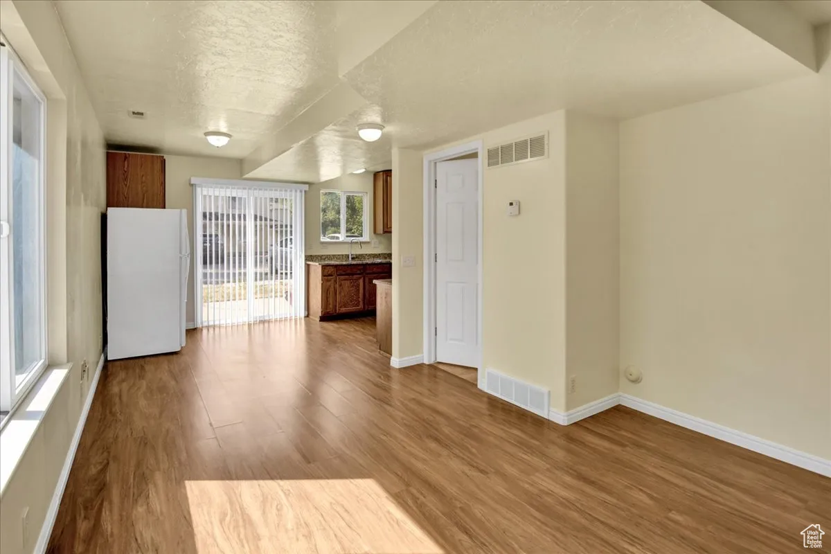 Kitchen featuring brown cabinets, freestanding refrigerator, a textured ceiling, and light wood-style flooring
