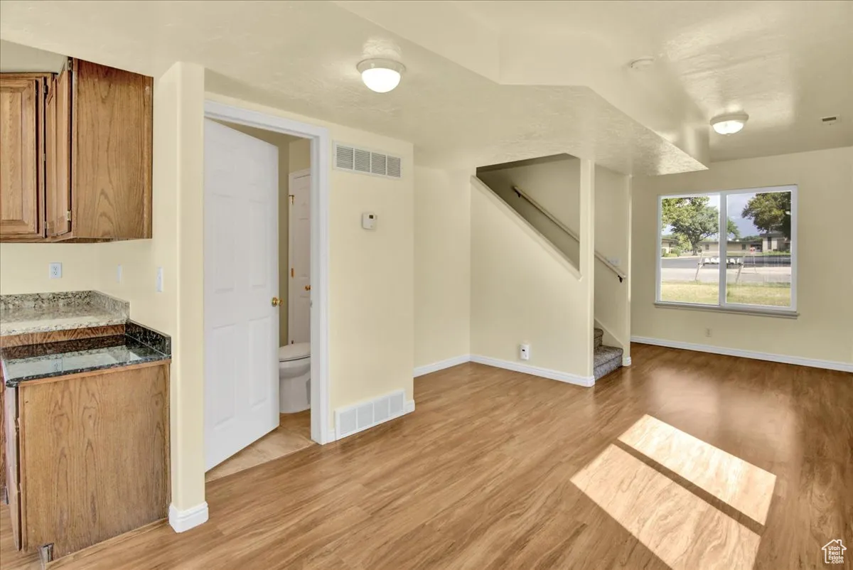 Unfurnished living room with stairs and light wood finished floors