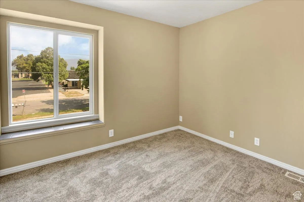 Empty room with baseboards and light colored carpet