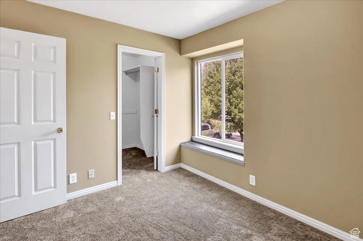 Unfurnished bedroom with a spacious closet and carpet