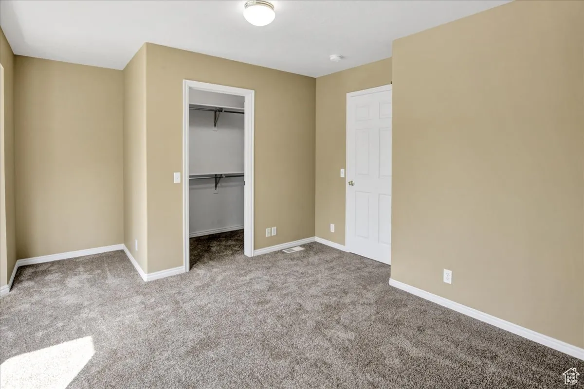 Unfurnished bedroom featuring a spacious closet and light colored carpet