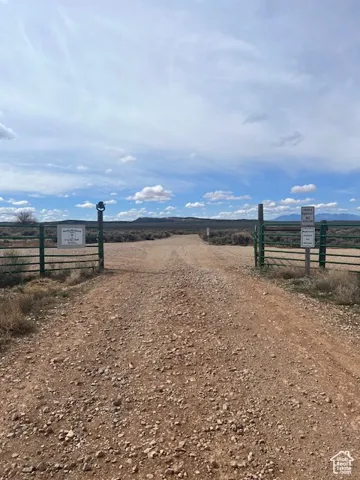 View of dirt / gravel driveway featuring a rural view and a gated entry