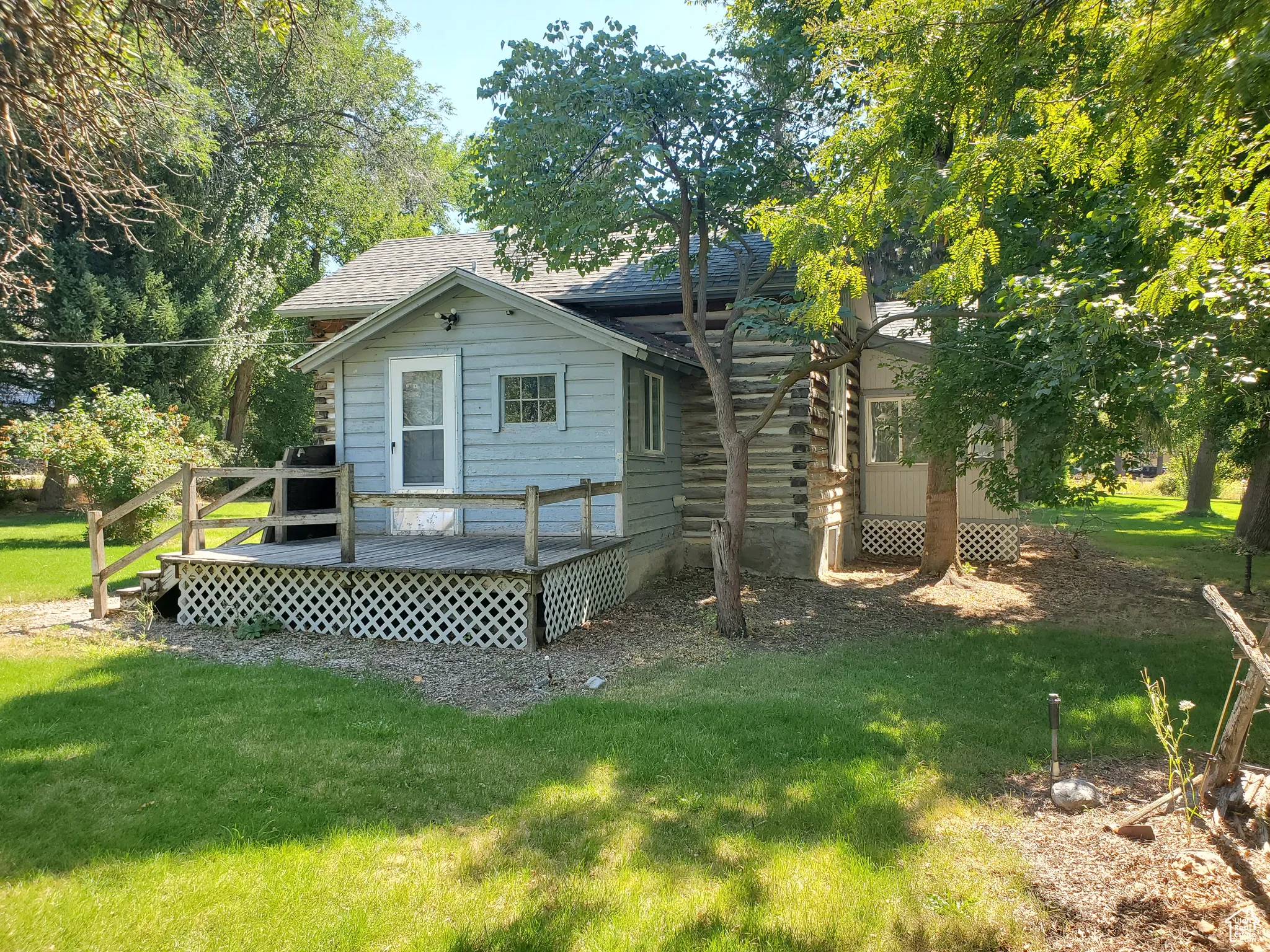 Rear view of property with a deck, a yard, and roof with shingles
