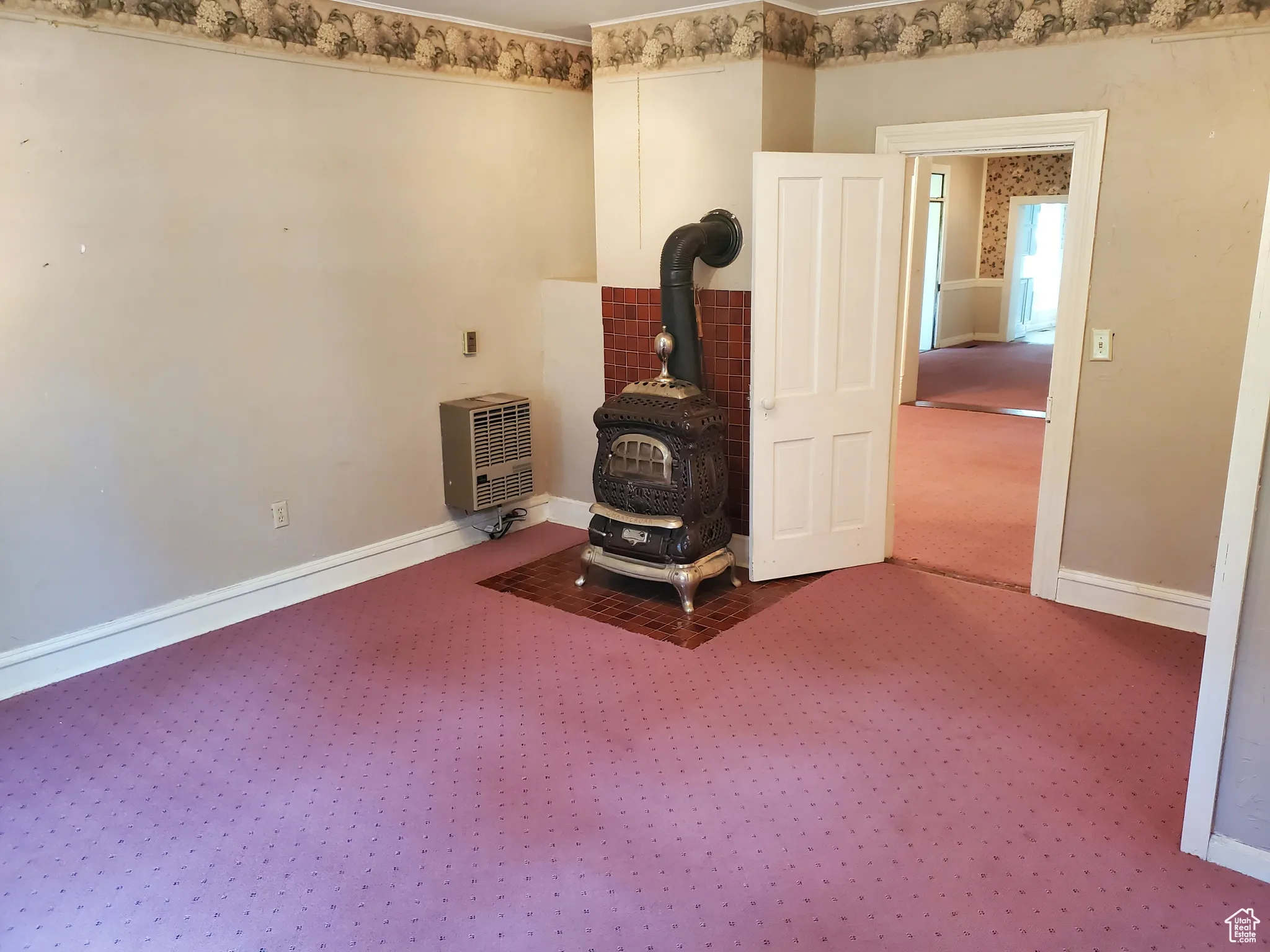 Unfurnished room with a wood stove, carpet, and heating unit