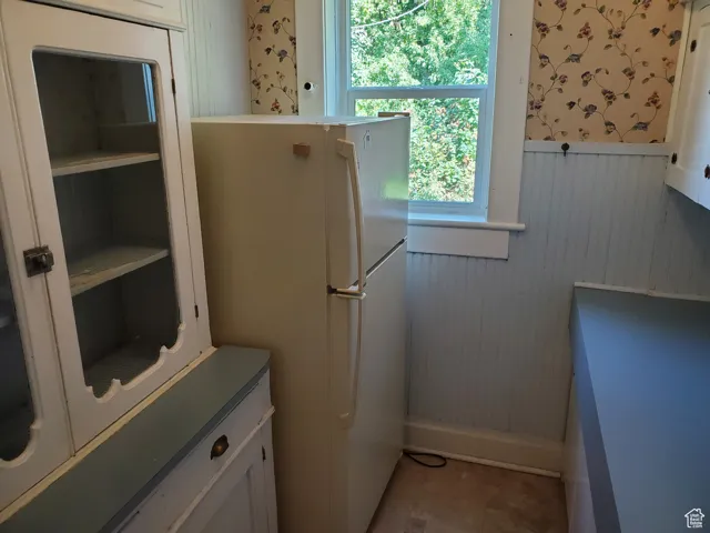 Laundry area featuring wallpapered walls and a wainscoted wall