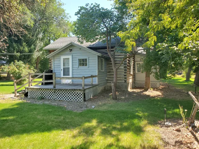 Rear view of property with a deck, a yard, and roof with shingles