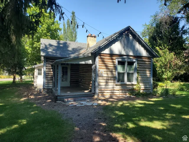 View of front of property with a front lawn, a chimney, and a shingled roof