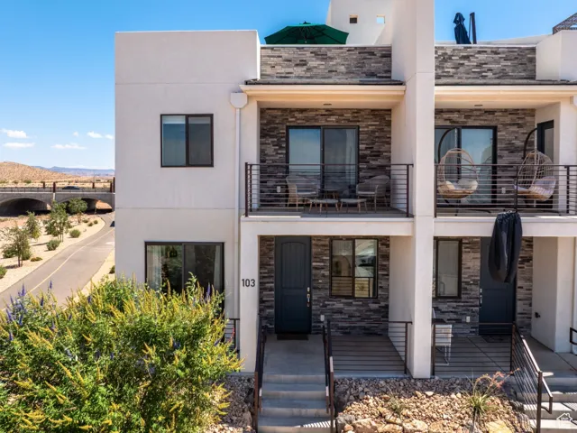 Contemporary house with stone siding, stucco siding, a mountain view, and a balcony