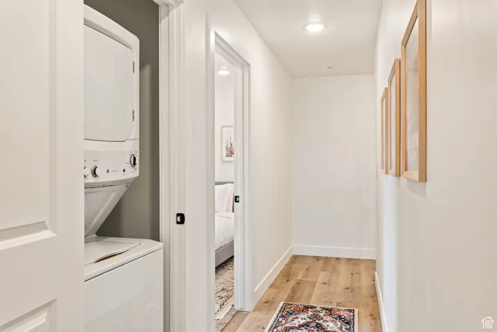 Laundry area with light wood finished floors and stacked washer and clothes dryer