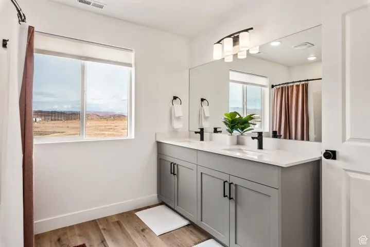 Full bath featuring double vanity, light wood-type flooring, recessed lighting, and curtained shower