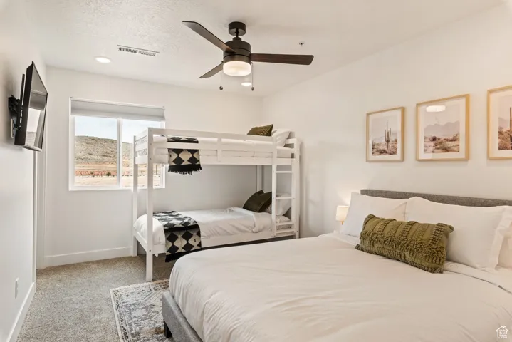 Bedroom featuring light carpet, a ceiling fan, and a textured ceiling
