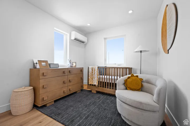 Bedroom with wood finished floors, recessed lighting, and a crib