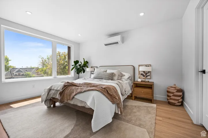 Bedroom featuring recessed lighting, light wood-type flooring, and a wall mounted air conditioner