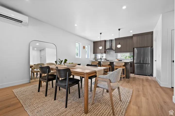 Dining space featuring a wall mounted air conditioner, light wood-type flooring, and recessed lighting
