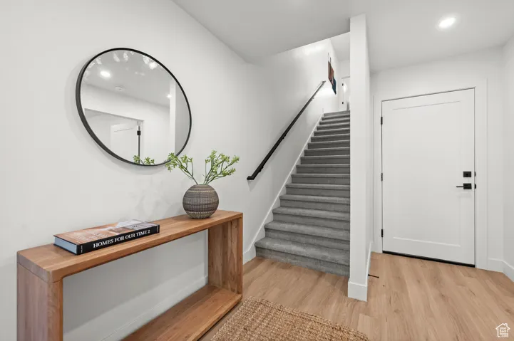 Stairs featuring wood finished floors and recessed lighting