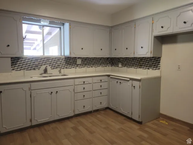 Kitchen featuring decorative backsplash, light countertops, and dark wood-type flooring