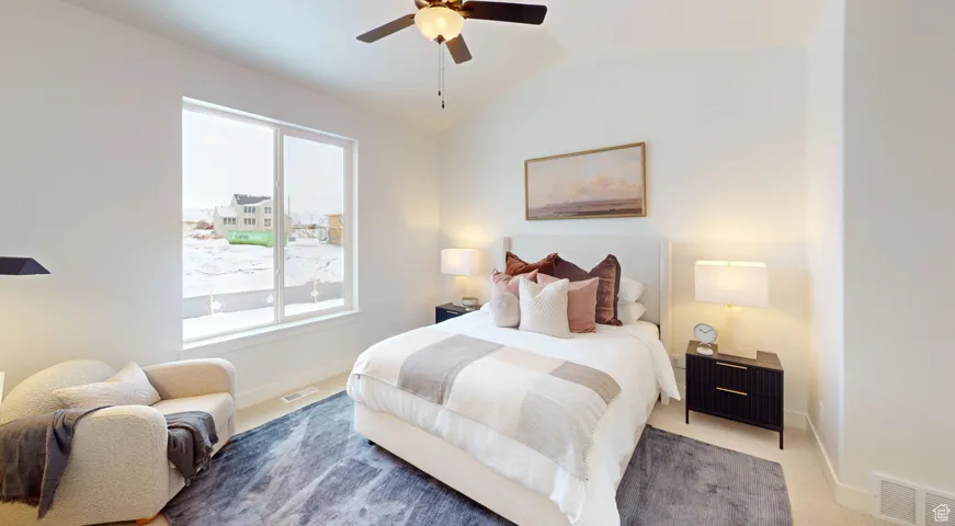 Carpeted bedroom with ceiling fan and vaulted ceiling