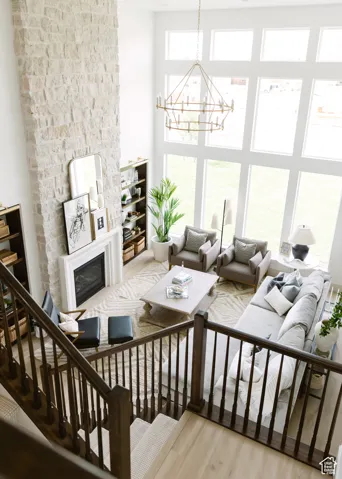 Living room featuring a glass covered fireplace, light wood-style floors, a chandelier, and a high ceiling