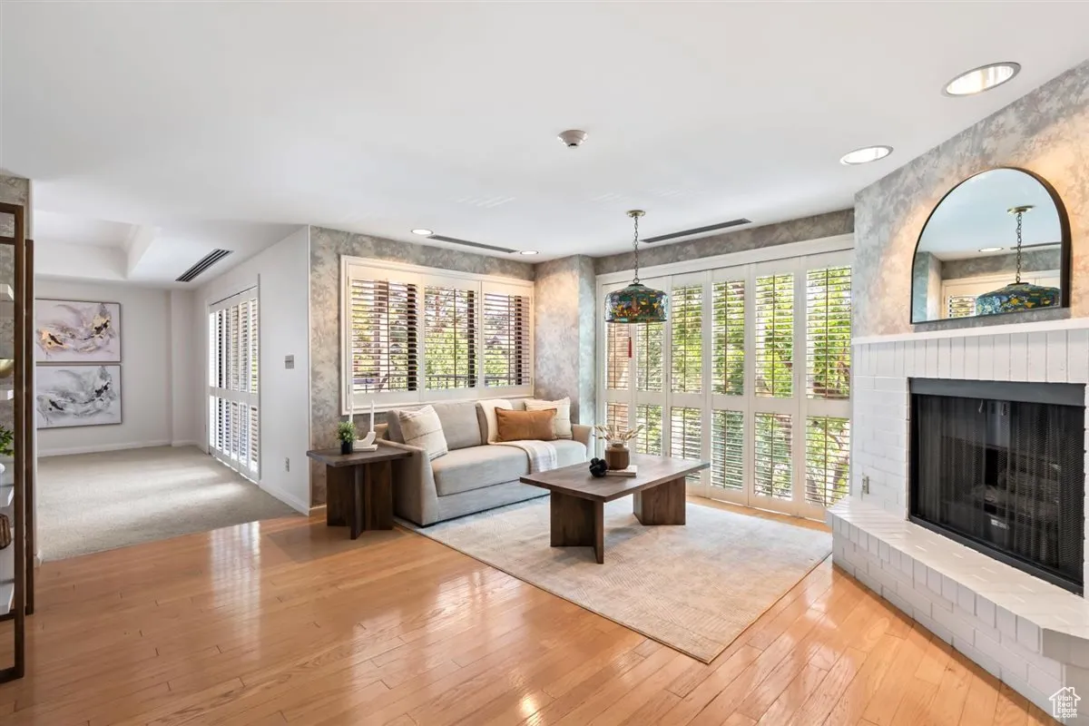 Living room with plenty of natural light, light wood-style flooring, a brick fireplace, and recessed lighting
