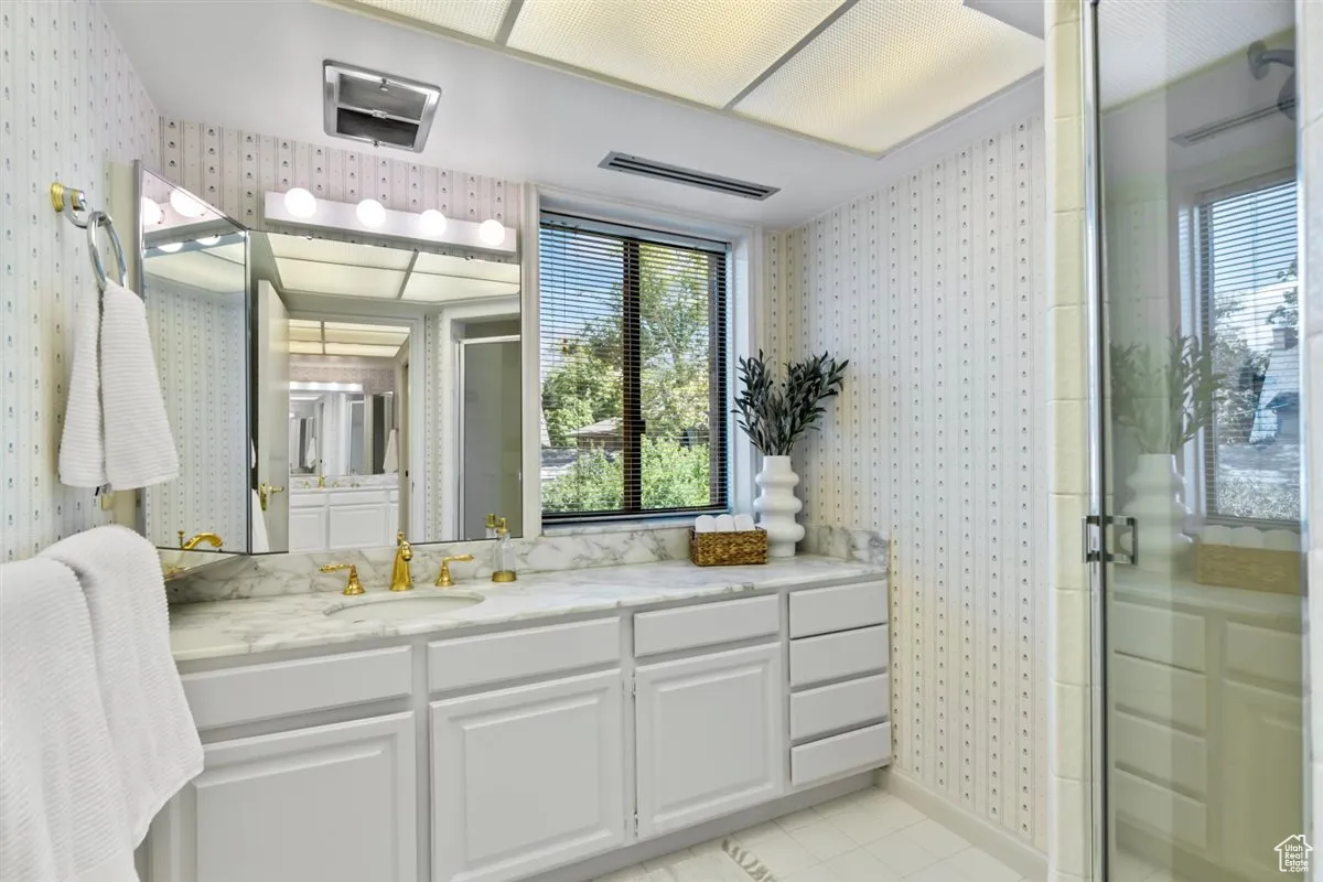 Full bathroom featuring wallpapered walls, vanity, a stall shower, and light tile patterned floors