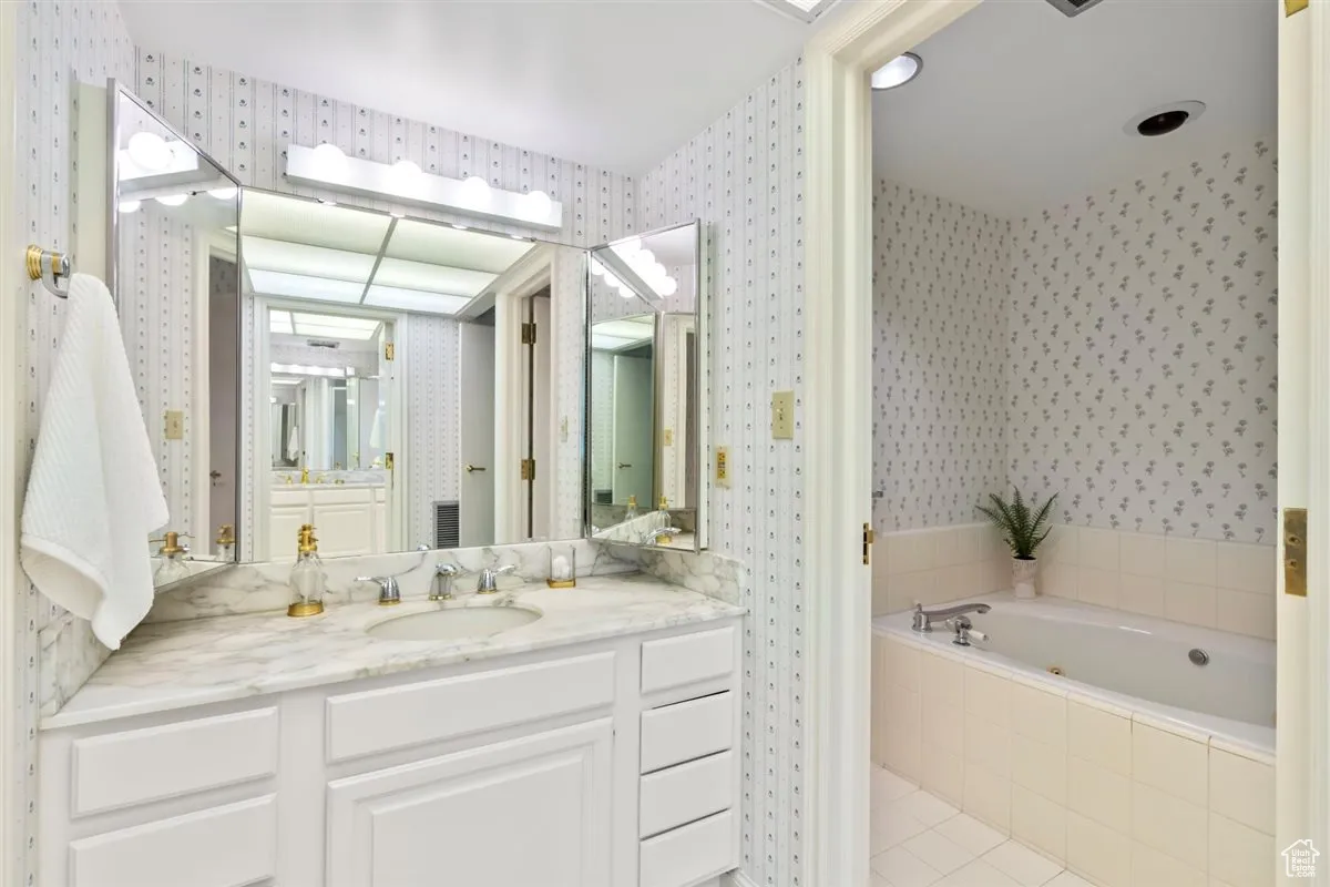 Bathroom featuring a garden tub, vanity, and light tile patterned flooring
