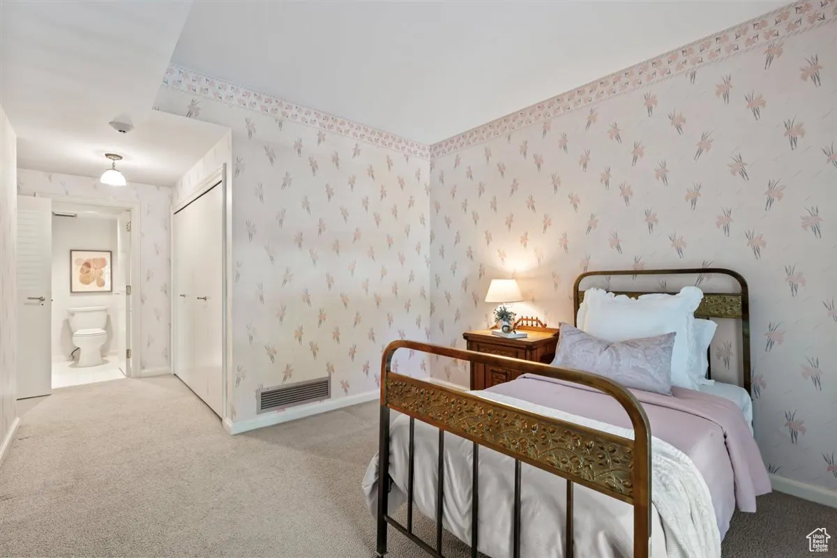 Bedroom featuring wallpapered walls, carpet, and connected bathroom
