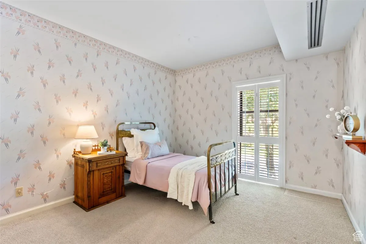 Bedroom with wallpapered walls and light colored carpet
