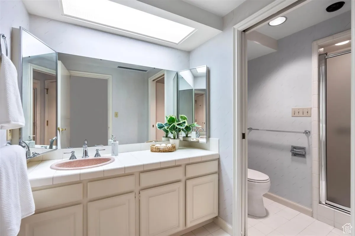 Full bath with a stall shower, vanity, and light tile patterned floors
