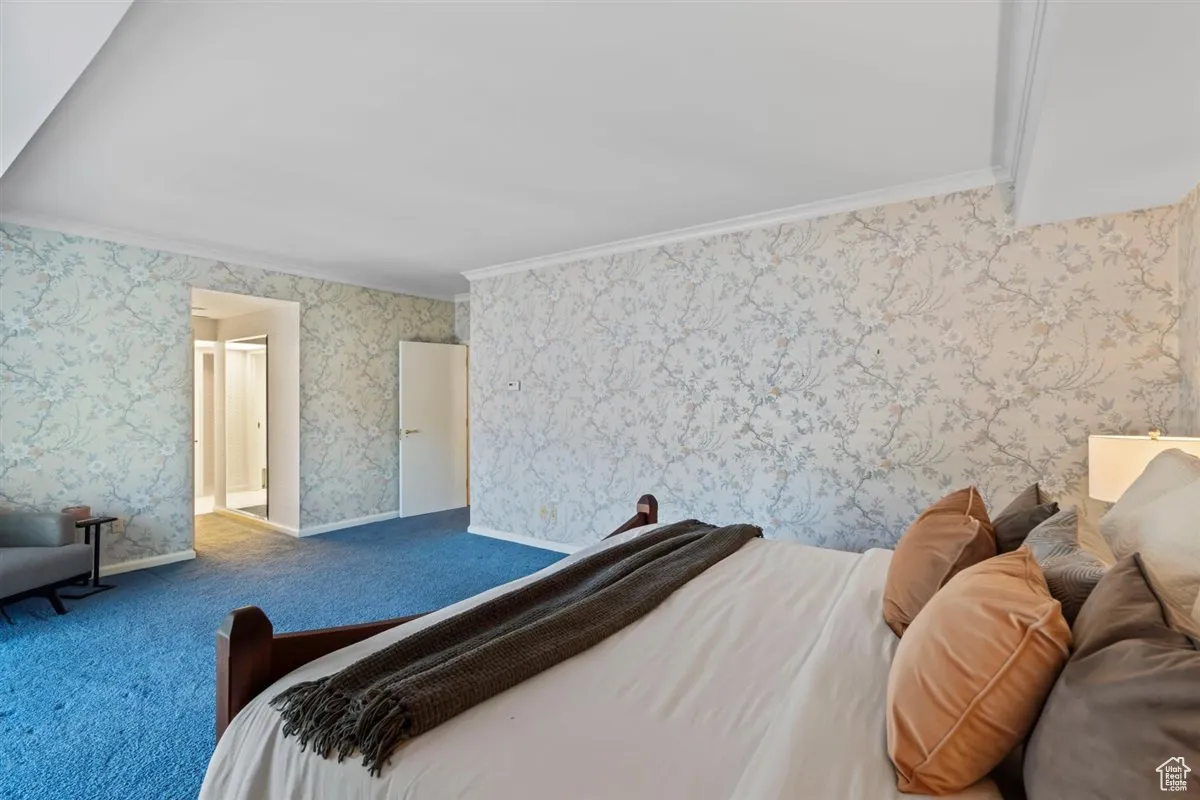Bedroom with crown molding, wallpapered walls, and carpet