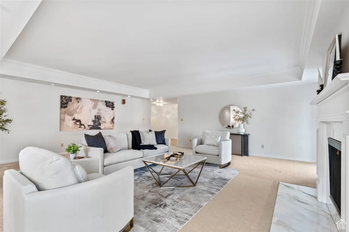 Living area featuring light colored carpet, a fireplace, and crown molding