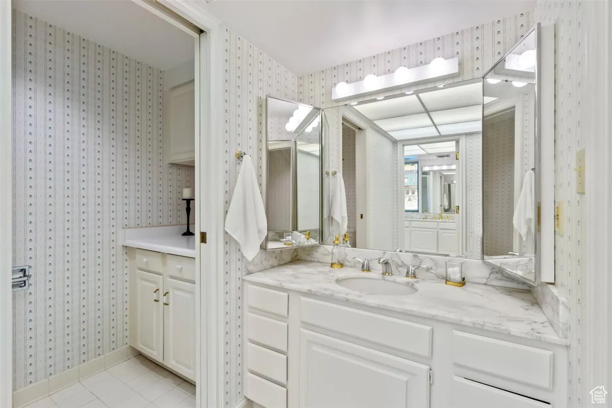 Full bath featuring vanity, wallpapered walls, and light tile patterned floors