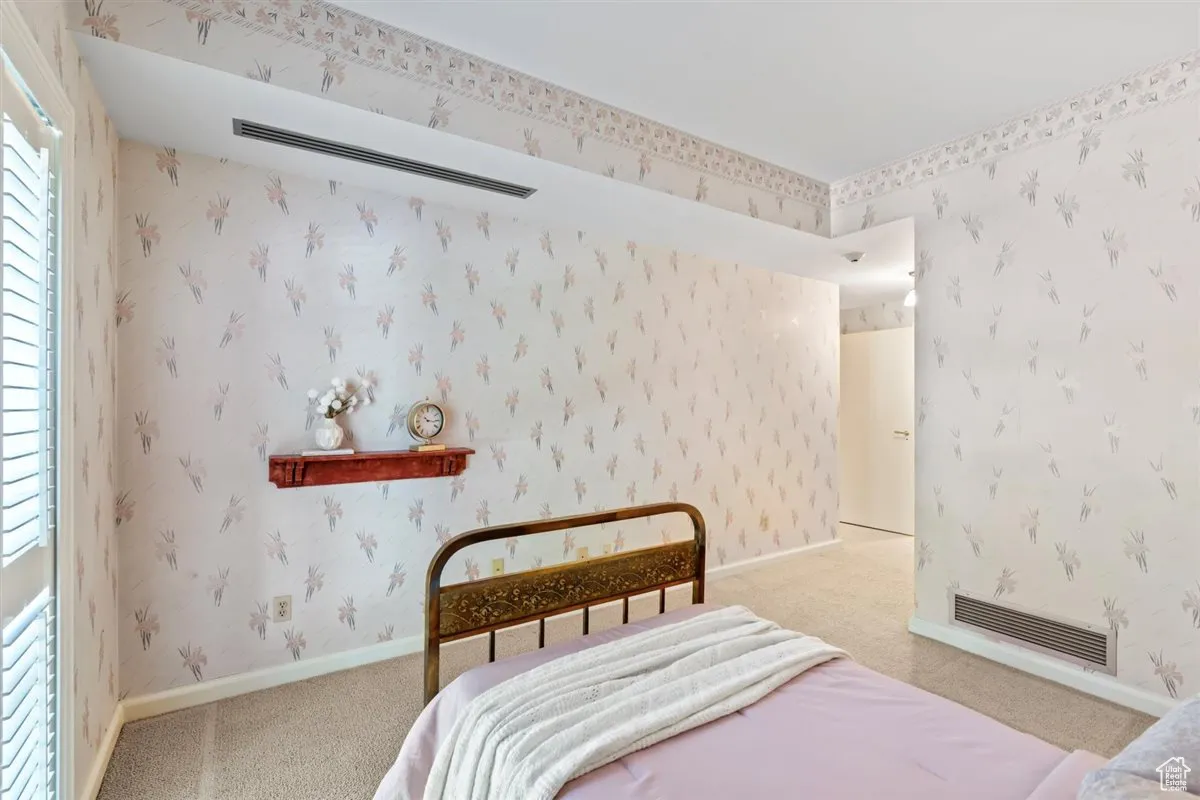 Bedroom featuring wallpapered walls and light carpet