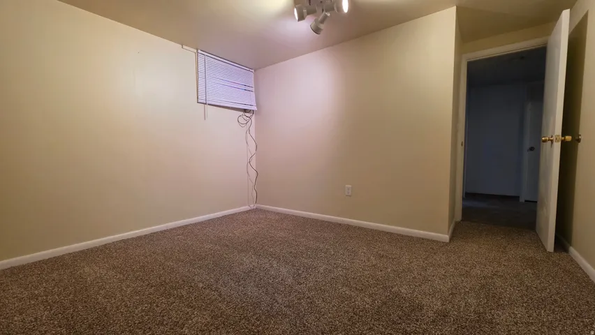 Carpeted interior room featuring neutral wall tones, baseboard trim, and a track lighting fixture