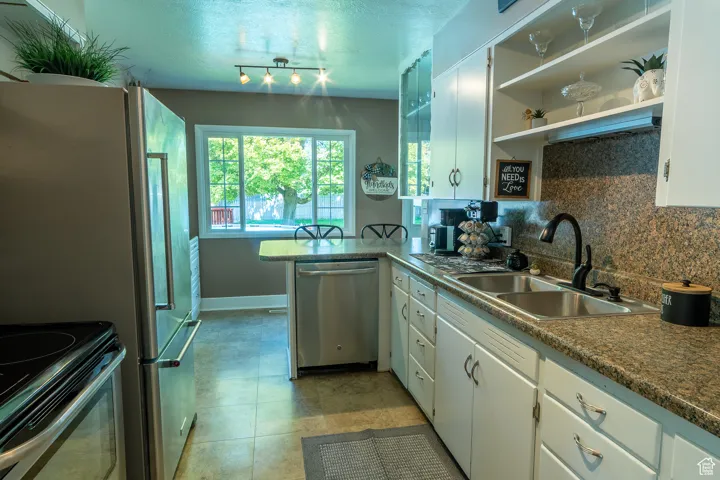 Kitchen featuring backsplash, open shelves, dishwasher, white cabinets,
