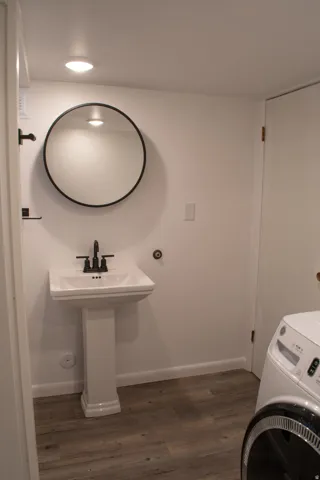 New Bathroom with Pedestal sink with matte black faucet, framed by a circular mirror, set against white walls