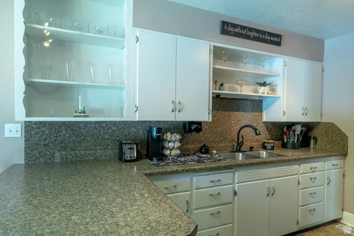 Kitchen with open shelves, decorative backsplash, white cabinetry,