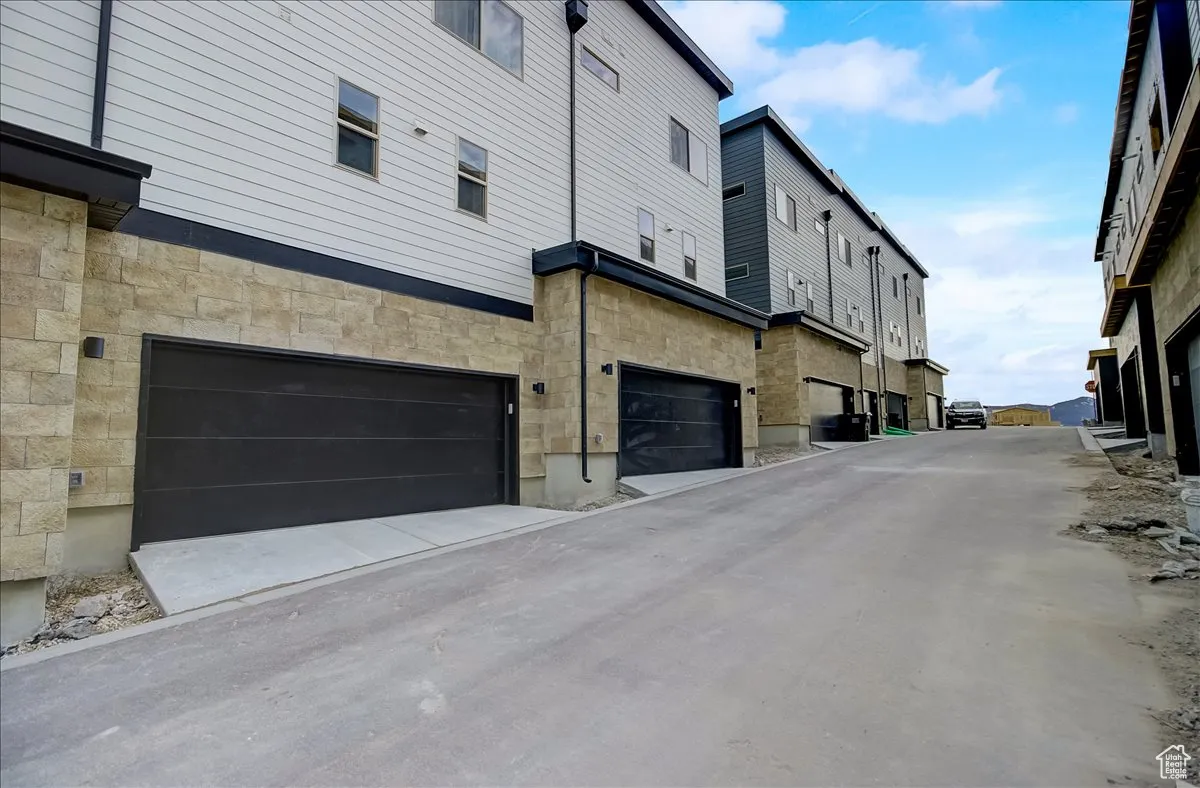 Rear view of property with stone siding and an attached garage