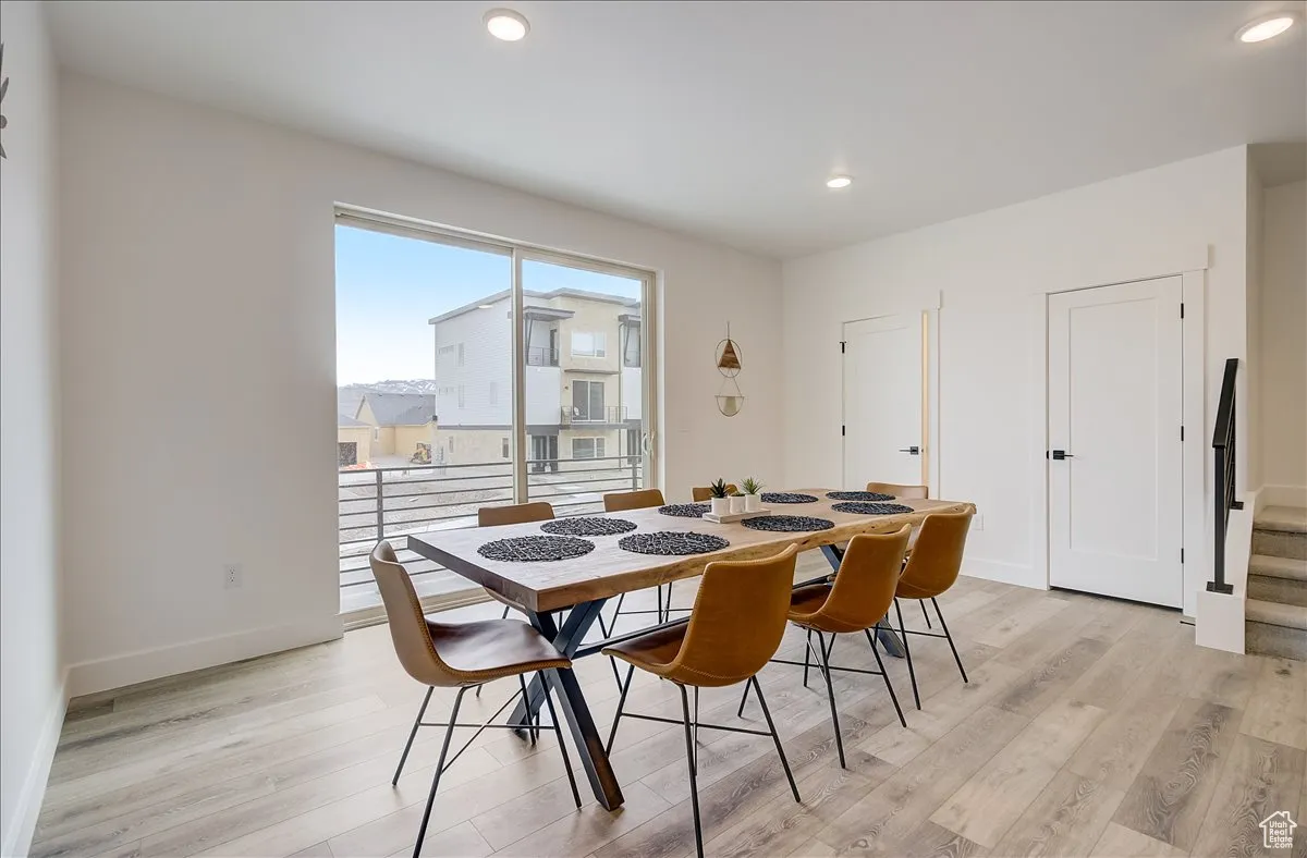 Dining area with light wood finished floors, recessed lighting, and stairway