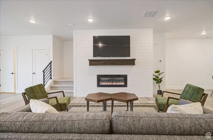 Living area with recessed lighting, wood finished floors, and a large fireplace