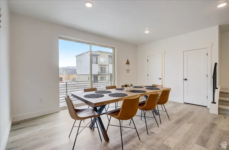 Dining area with light wood finished floors, recessed lighting, and stairway