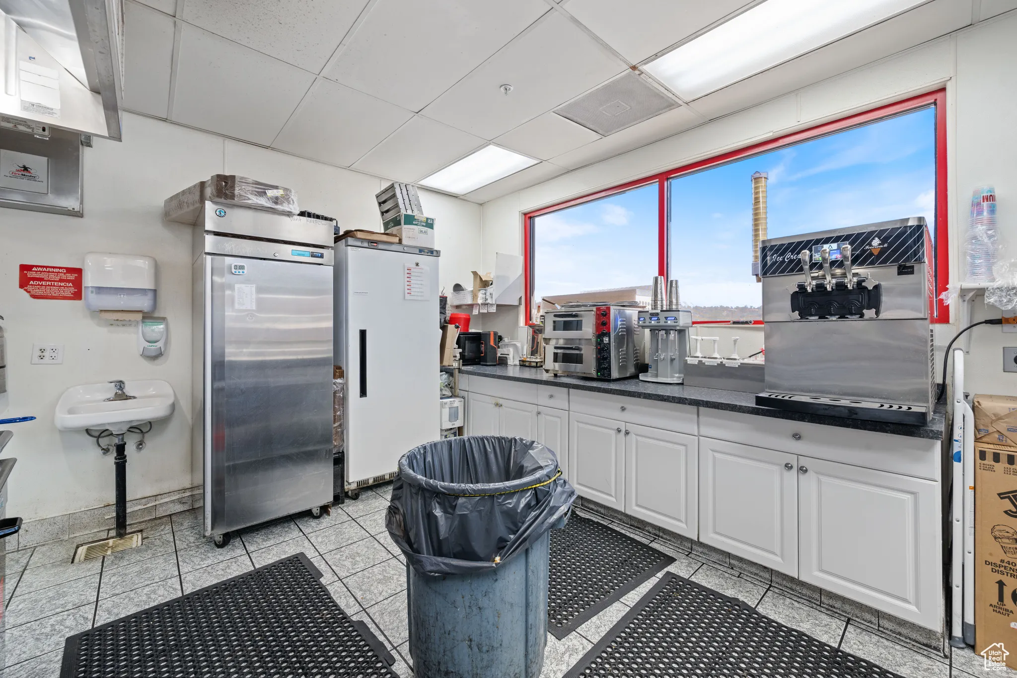 Kitchen with a drop ceiling, white cabinetry, freestanding refrigerator, light tile patterned floors, and stainless steel fridge