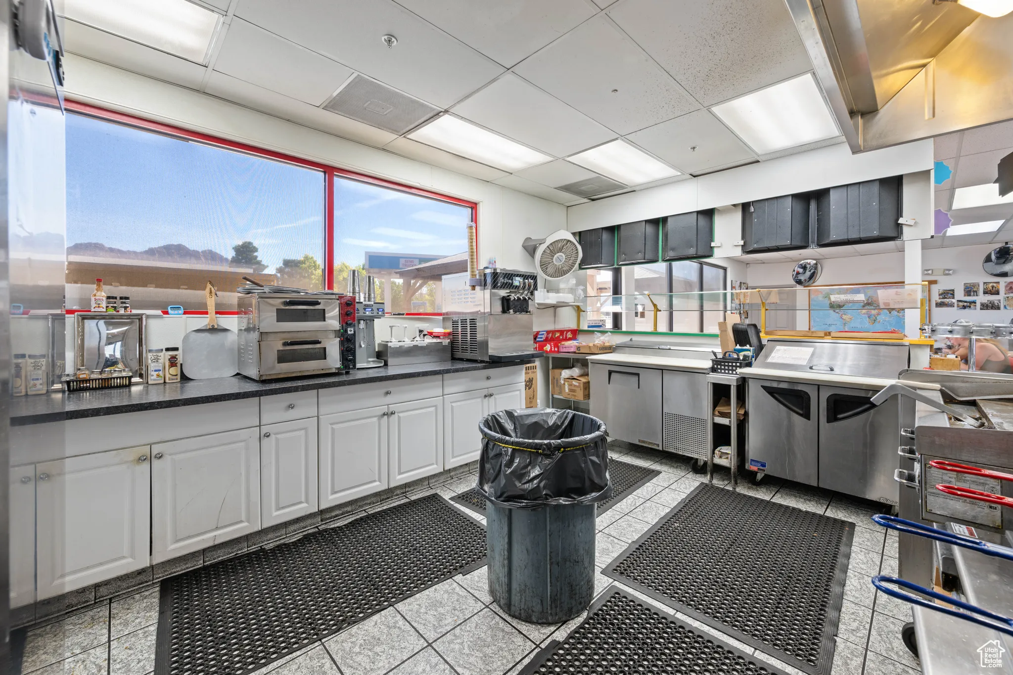 Kitchen with dark countertops, white cabinetry, a paneled ceiling, and light tile patterned floors