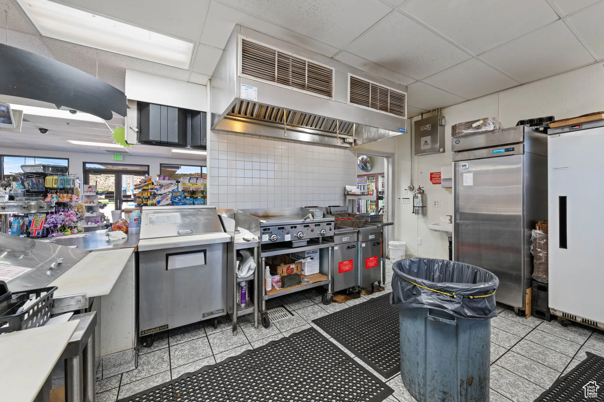 Kitchen with a paneled ceiling, extractor fan, white fridge, light countertops, and light tile patterned floors