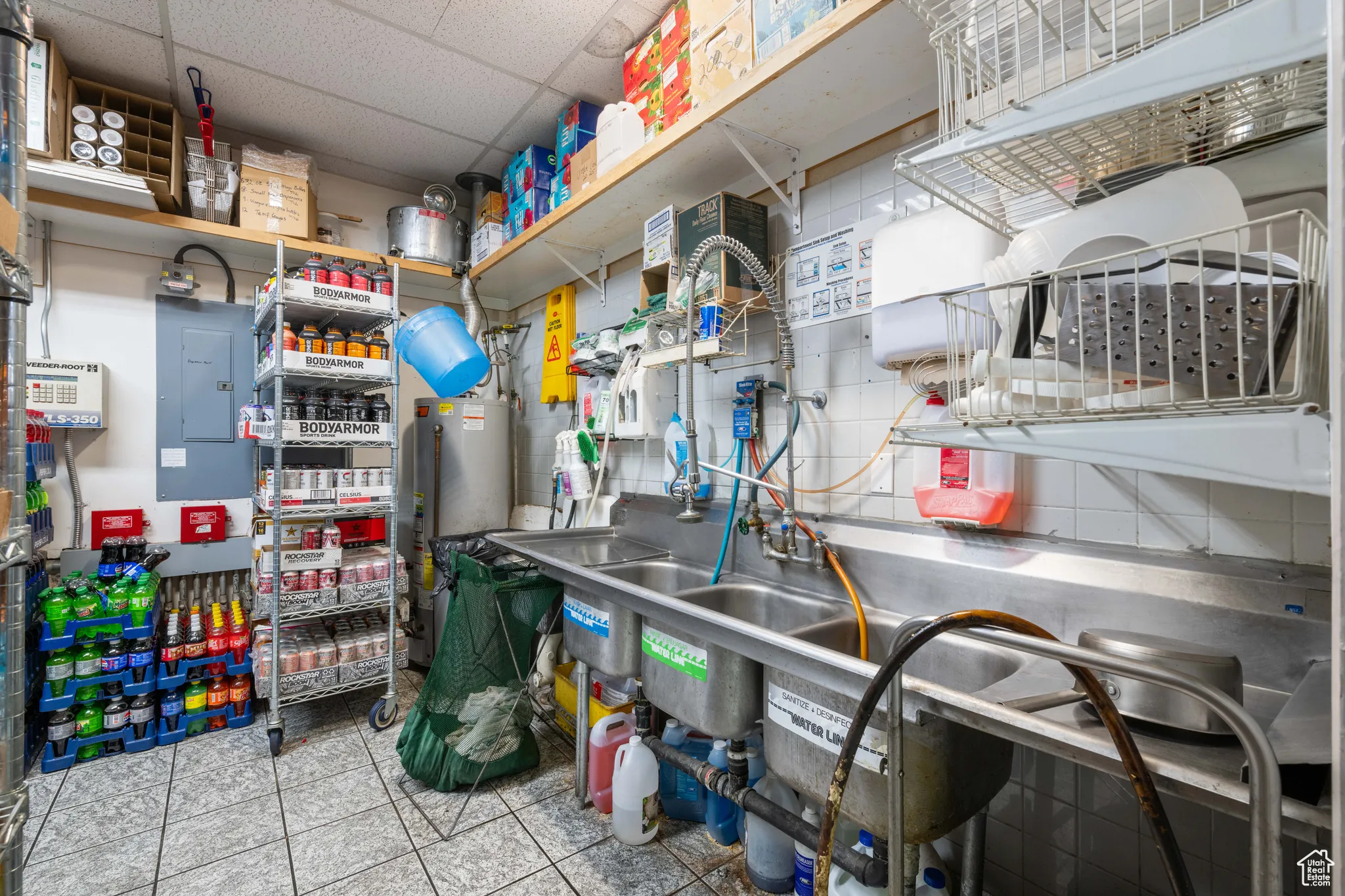 Kitchen featuring electric panel, gas water heater, light tile patterned floors, and a paneled ceiling